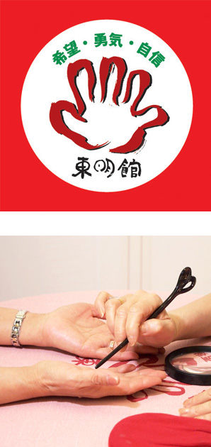 写真の上段：東明館のロゴマーク/下段：黒い指し棒を使って両手の手相占いの鑑定中