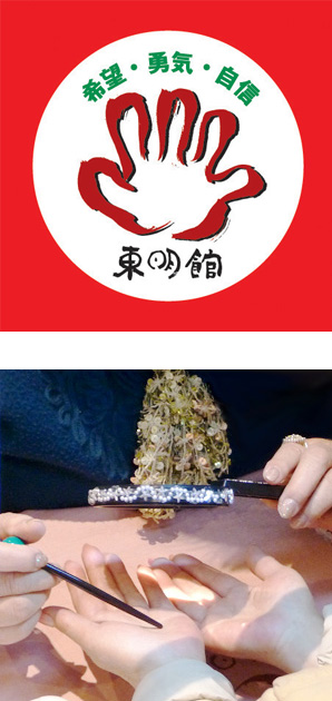 写真の上段:東明館のロゴマーク/下段:パールやビーズで装飾されたルーペと緑の玉がついた指し棒で手相占いの鑑定中