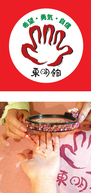 写真の上段:東明館のロゴマーク/下段:ピンクのきらきらで装飾したルーペと指し棒を使って手相占いの鑑定中
